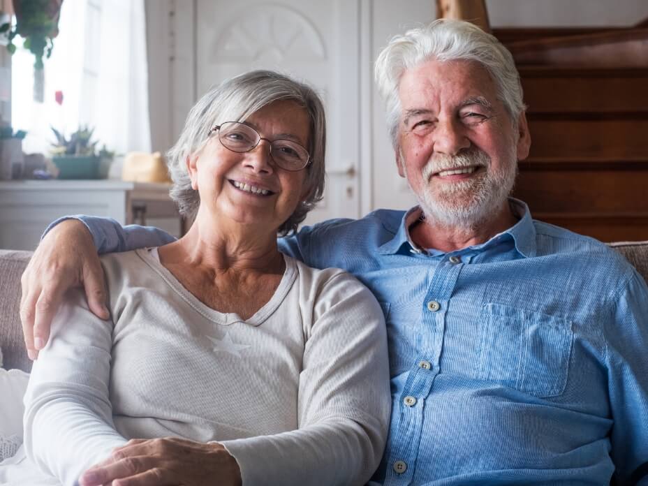 Ein älteres Paar sitzt glücklich nebeneinander auf einem Sofa