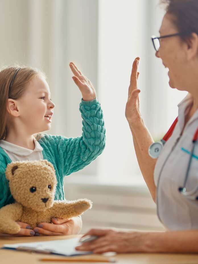Ärztin mit Kind das einen Teddy-Bären hält