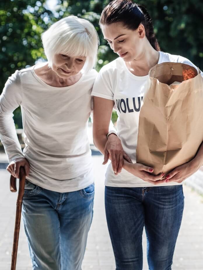 Einer Seniorin wird beim tragen ihrer Einkäufe geholfen