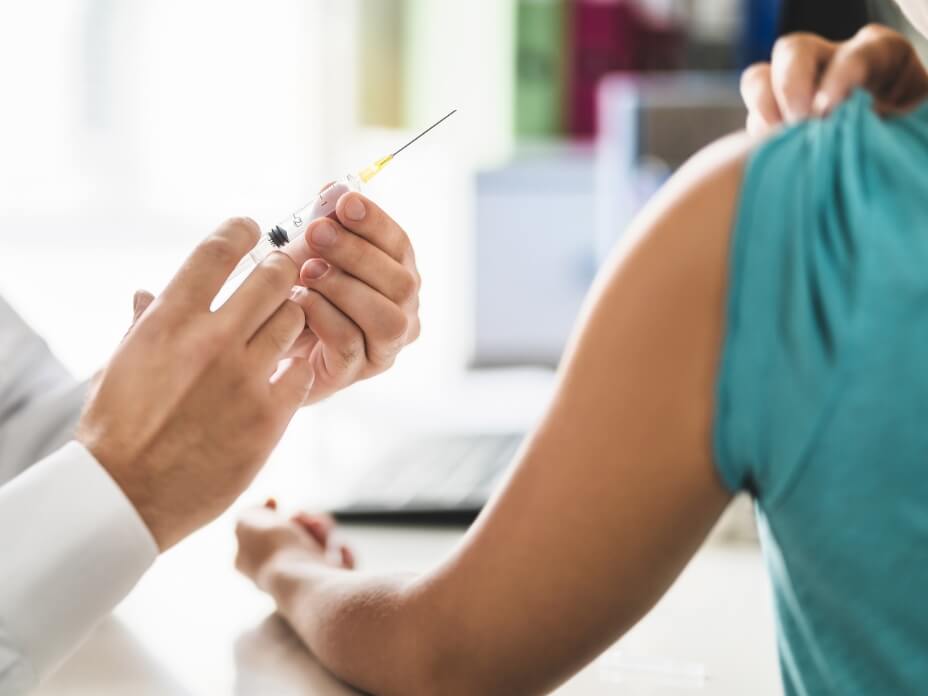 Arzt beim ansetzen einer Impf-Spritze am Oberarm